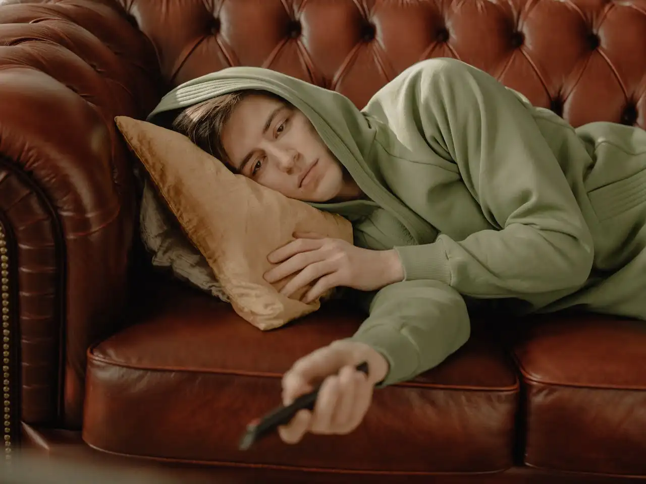 A bored person lying on a sofa watching TV